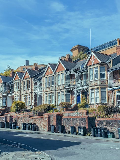 Image of a three-storey residential house with a yellow brick facade, featuring white decorative window surrounds and a pitched dark roof. The ground floor has a white front door with a small window a